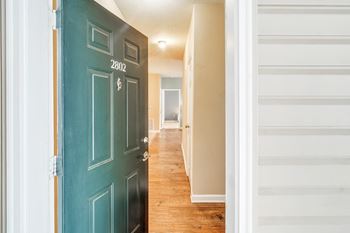 A view of a hallway with a green door and a hall way with a staircase